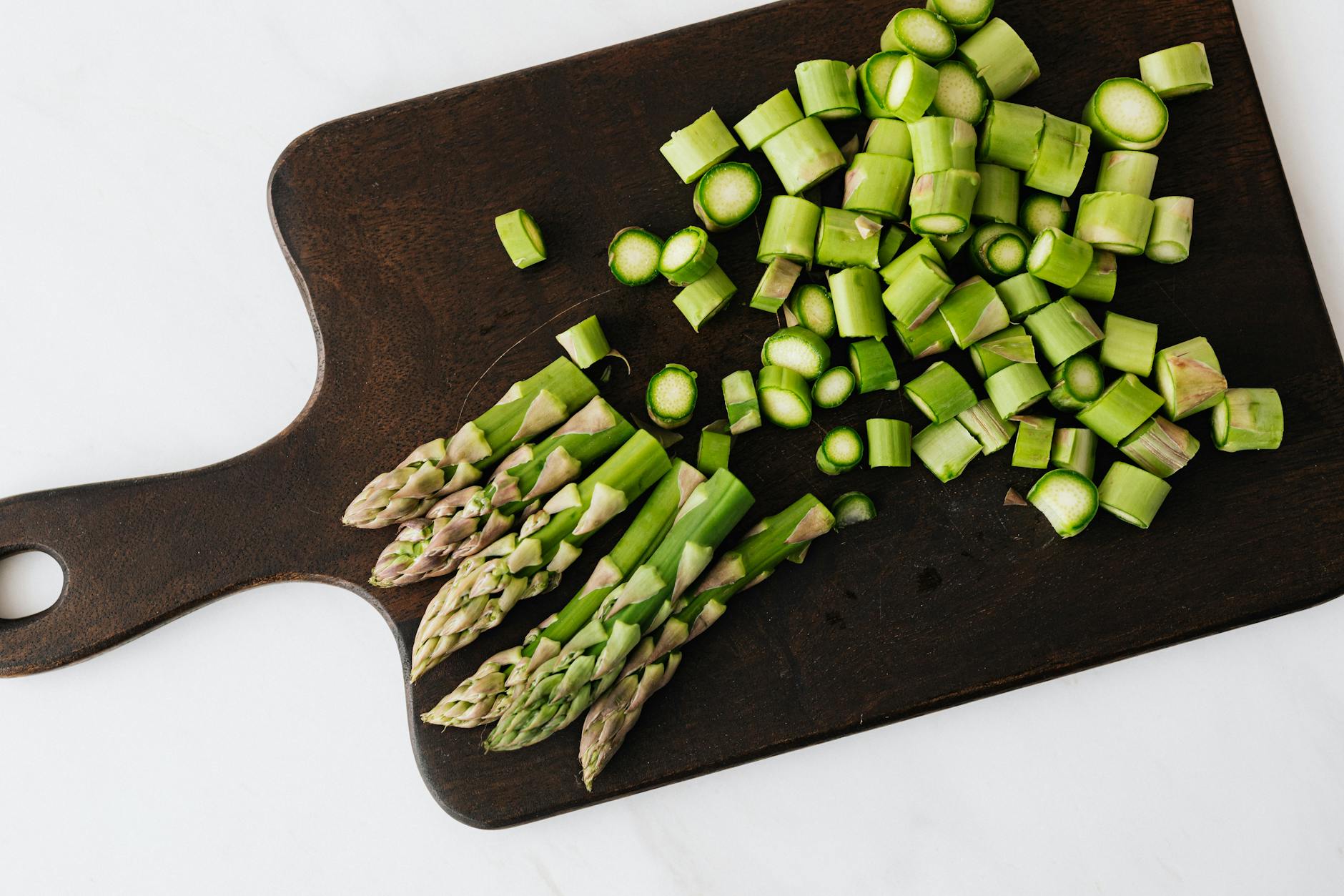 green chopped asparagus on wooden board in kitchen